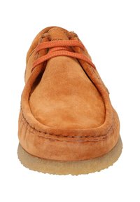 Chaussure en daim orange avec un bout rond, dotée de lacets orange et d'une semelle en caoutchouc texturé couleur tan. Coutures visibles le long des bords.