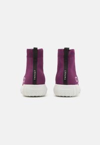 Purple knit ankle boots with black heel tab, white rubber sole, and logo detailing. The upper has a snug fit and textured appearance.