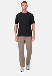 Crno kratkoslvno majico uparjeno s svijetlosmeđim, uskim hlačama. Oba komada su izrađena od mekanog materijala; modeli su obuli sive sportske cipele.