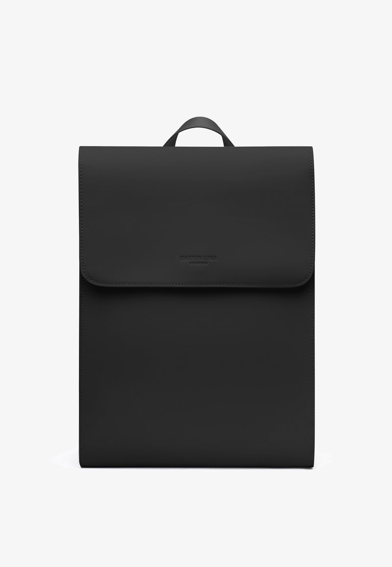 Sac à dos rectangulaire noir avec fermeture à rabat et poignée supérieure, arborant un logo de marque embossé discret au centre avant.