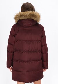 Burgundská péřová bunda s kapucí z falešné kožešiny, s prošívanými částmi a dlouhými rukávy, navržena pro teplo a pohodlí.