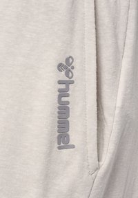 Light gray fabric featuring a fine texture with a subtle pattern. A gray logo with stylized letters is positioned vertically on the side.
