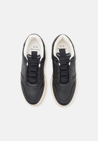 Sorte lær sneakers med teksturert overflate, som har elastiske snøringer, polstret krage og en kremfarget gummisåle. Logo på innersålen.