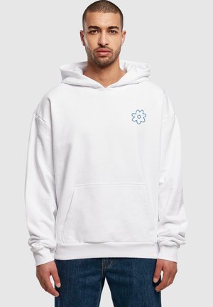 Hvid hættebluse med en forlommes, oversized design, der har et blåt blomsterlogo på venstre bryst og ribbede manchetter og kant.