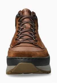 Chaussure en suédé marron avec des accents en cuir, œillets en métal, semelle en caoutchouc noir épais et détails de couture contrastés.