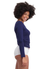 Marineblaues Langarmoberteil mit figurbetonter Passform, aus weichem Material, kombiniert mit weißer Unterwäsche mit einem markierten Bund.