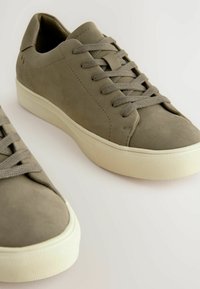 Baskets en suede gris avec bout rond, lacets plats et semelle en caoutchouc texturé. Design minimaliste avec des tons neutres ; détail de couture subtil.