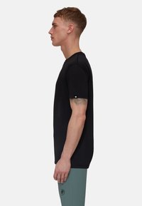 Zwarte t-shirt met korte mouwen en een ronde hals, gemaakt van lichtgewicht stof, met een klein logodetail op de linkermouw.