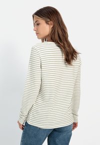 Stribet langærmet skjorte i lys beige med olivengrønne striber, med rund halsudskæring og en afslappet pasform. Blødt, tekstureret stof.
