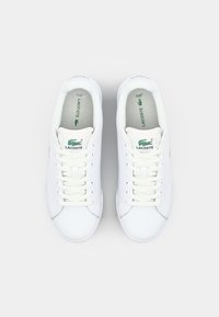 Tênis brancos de couro com bico arredondado, atacadores planos e detalhes em verde no logotipo. Interior forrado suavemente com um design minimalista.