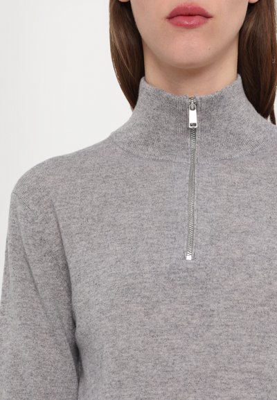 Γκρι πλεκτός πούλος με ψηλό λαιμό και ασημένιο φερμουάρ. Το ύφασμα φαίνεται μαλακό, με μια διακριτική υφή και στενή γραμμή.