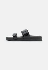 Svarta slide-sandaler med en mjuk, glänsande yta och två justerbara remmar. Sulan är platt och slitstark, utformad för komfort.