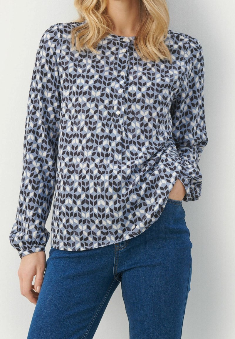 Blusa a maniche lunghe con un motivo geometrico nei toni di blu, grigio e nero. Presenta un collo rotondo e una chiusura frontale con bottoni. Tessuto morbido.