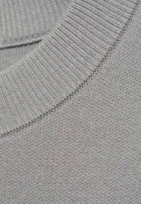 Grauer Strickstoff mit einem gerippten Rundhalsausschnitt. Die Textur ist glatt und gleichmäßig, mit feinen, eng gewebten Stichen.
