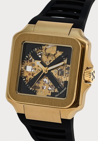 Montre-bracelet carrée en or avec engrenages mécaniques visibles, aiguilles noires des heures et des minutes, bracelet noir et logo "Off-White" sur le cadran.