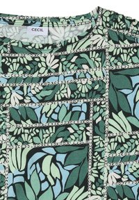 Tkanina w zielone, niebieskie i białe wzory kwiatowe z liniami siatki w formie łańcucha oraz marszczeniem w pobliżu ramienia.