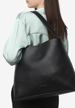 Borsa a mano nera in pelle con una texture liscia, una sola tracolla e design minimalista. Presenta un logo discreto vicino al fondo.