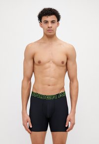Čierne boxerky pre mužov s priliehavým strihom, vyrobené z hladkého materiálu, s širokým neónovo zeleným elastickým pásom "UNDER ARMOUR".