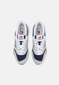 Sneakers con un design grigio, blu navy e rosso, realizzati in materiali mesh e suede, con lacci bianchi e un logo prominente sul tallone.