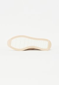 Semelle de chaussure avec un design texturé, composée d'un matériau en caoutchouc beige clair et d'un motif de bande de roulement blanc détaillé pour une adhérence optimale.