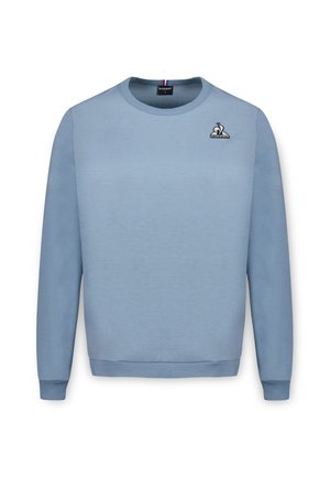 Light blue crewneck sweatshirt made of soft cotton material. Features ribbed cuffs, hem, and a small embroidered logo on the chest.