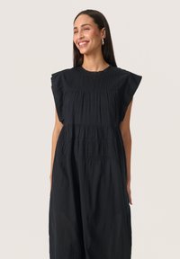 Schwarzes Kleid mit kurzen, rüschierten Ärmeln, Rundhalsausschnitt und strukturiertem Stoff mit gestuften Falten und Spitzenakzenten.