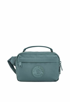 Sac banane compact bleu sarcelle avec poignée supérieure, poche zippée à l'avant, et patch logo rond portant l'inscription "Fjällräven Kånken" sur fond blanc.