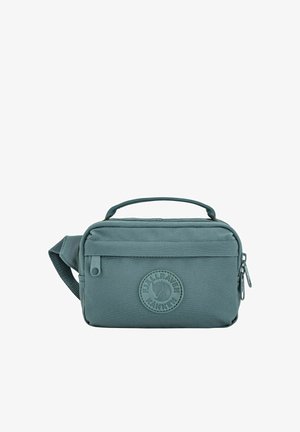 Sac banane compact bleu sarcelle avec poignée supérieure, poche zippée à l'avant, et patch logo rond portant l'inscription "Fjällräven Kånken" sur fond blanc.