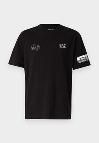 Black t-shirt made of cotton, featuring a small white EA7 logo on the chest and a textured graphic design on the left sleeve.