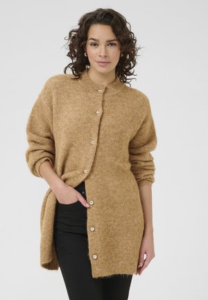 Long gilet douillet en tissu tricoté brun doux. Présente un col rond, une fermeture à boutons à l'avant et des manches retroussées. Design simple et décontracté.