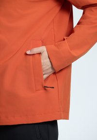 Orange jacket made of smooth fabric, featuring a side pocket and a relaxed fit. It has a straight hem and long sleeves.