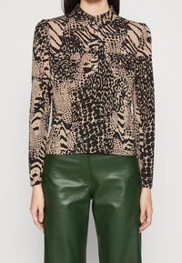 Lange mouwen blouse in beige met zwart dierenprint, met een kraag en knoopsluiting aan de voorkant. Glad materiaal, slim fit en geen gedefinieerde taille.