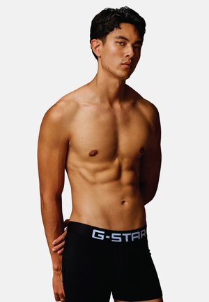 Boxer-briefs G-Star noirs avec une large taille arborant le logo de la marque en blanc. Design ajusté mettant en valeur une texture de matière lisse.