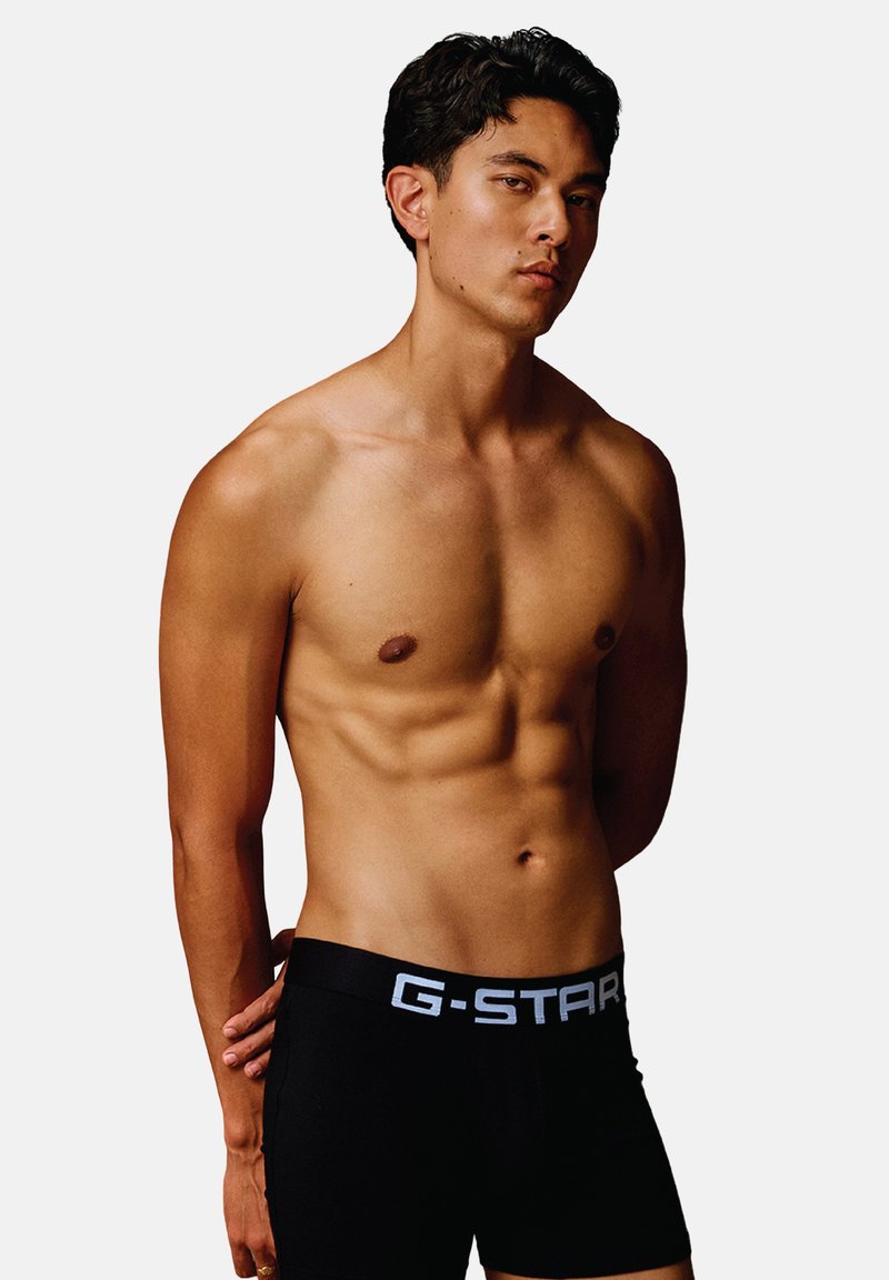 Black G-Star boxer briefs with a wide waistband featuring the brand logo in white. Close-fitting design showcases a smooth material texture.