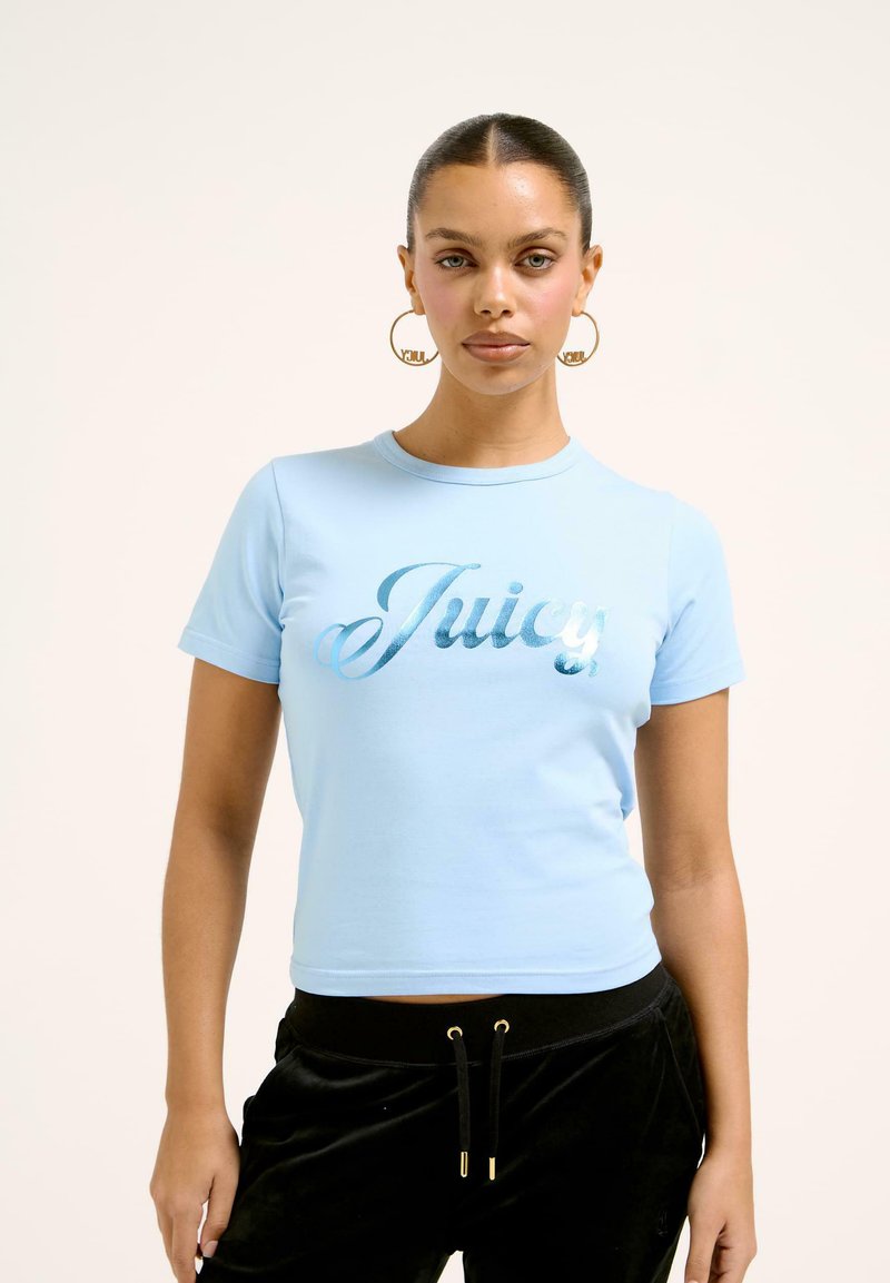 Világoskék, rövid ujjú, környakú, puha pamutból készült crop t-shirt, amelyen csillogó fémes "Juicy" felirat látható, szép írásos betűtípussal.
