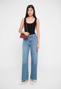 Sort ribbet tanktop, lyseblå vide jeans, hvide spidse højhælede sko og en lille bordeaux crossbody taske. Enkel, afslappet sæt.