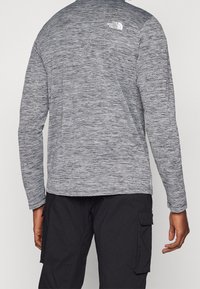 Langärmliges, meliertes graues Shirt aus strukturiertem Stoff, mit kleinem weißem Logo auf der Rückseite und Rundhalsausschnitt.