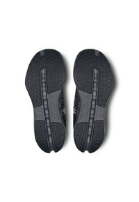 Schwarze Gummischuhsohlen mit strukturierten Grip-Mustern und erhabenen Akzenten, die eine zentrale Rille und eine stromlinienförmige Form für Flexibilität aufweisen.