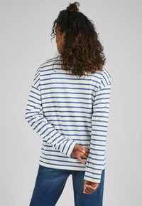 Maglietta a maniche lunghe a righe in crema e blu, con una vestibilità rilassata e in morbido cotone. La vista dal retro mostra maniche lunghe e un colletto rotondo.