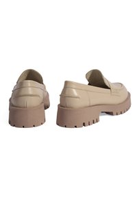 Mocassins en cuir beige avec un bout arrondi, un panneau texturé et une semelle en caoutchouc marron chunky avec des rainures profondes pour une meilleure traction.