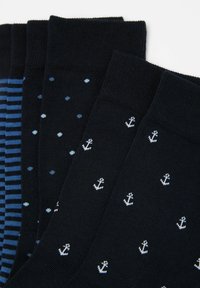 Vier Paare schwarze Socken mit unterschiedlichen Mustern: Ein Paar hat blaue Streifen, ein anderes hat Tupfen, und zwei zeigen Ankerdesigns.