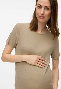 Camiseta materna de color beige claro, con cuello redondo, mangas cortas y textura suave, ligeramente ajustada en la cintura.