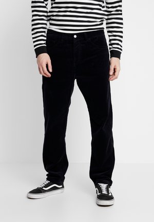 Dark blue corduroy pants feature a straight-leg cut, pockets, and a front button closure. Worn with a black and white striped long-sleeve shirt.