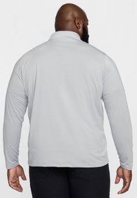 Világosszürke, hosszú ujjú pólóing hamis gallérral és finom bordázott textúrával. Laza szabású és lapos varrásokkal rendelkezik.