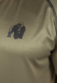 Olijfgroene sportshirt met korte mouwen, met op de voorkant een zwarte gorilla-afbeelding. Glad materiaal met subtiele textuurdetails.