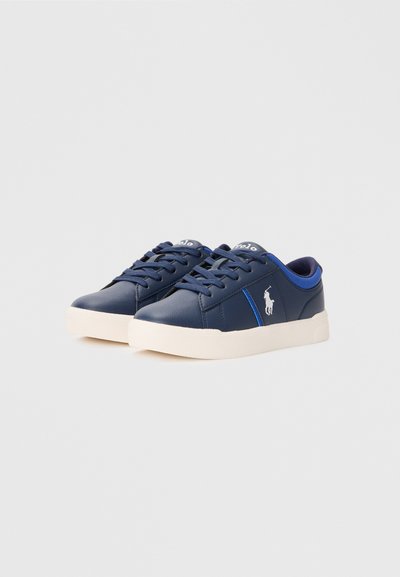 Sapatilhas sintéticas azul marinho com sola de borracha branca, design com atacadores, apresentando uma risca de destaque azul e logótipo na lateral.