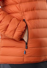 Oranje pufferjack met gequiltde textuur, ritszakken en een soepele afwerking. Inclusief een stoffen label met de merknaam aan de zoom.