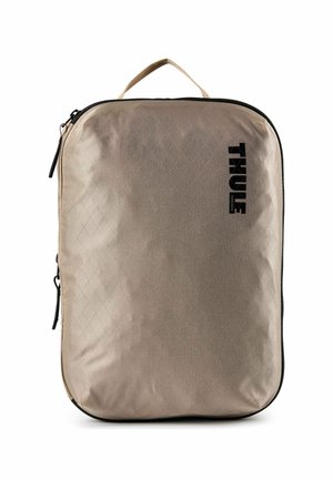 Cube da imballaggio Thule rettangolare beige con cerniere nere, una maniglia superiore e il logo Thule sul lato destro anteriore.