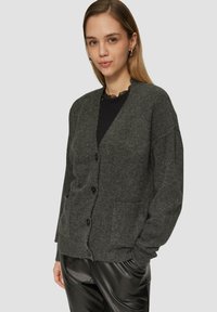 Dunkelgrauer Cardigan aus weichem, strukturiertem Material, mit V-Ausschnitt, sechs Knöpfen und zwei Vorderaschen. Lockerer Schnitt und lange Ärmeln.