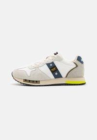 Sneaker caratterizzati da una combinazione di tessuto bianco e suede beige, con un pannello blu e un accento giallo sulla suola. Design atletico classico.